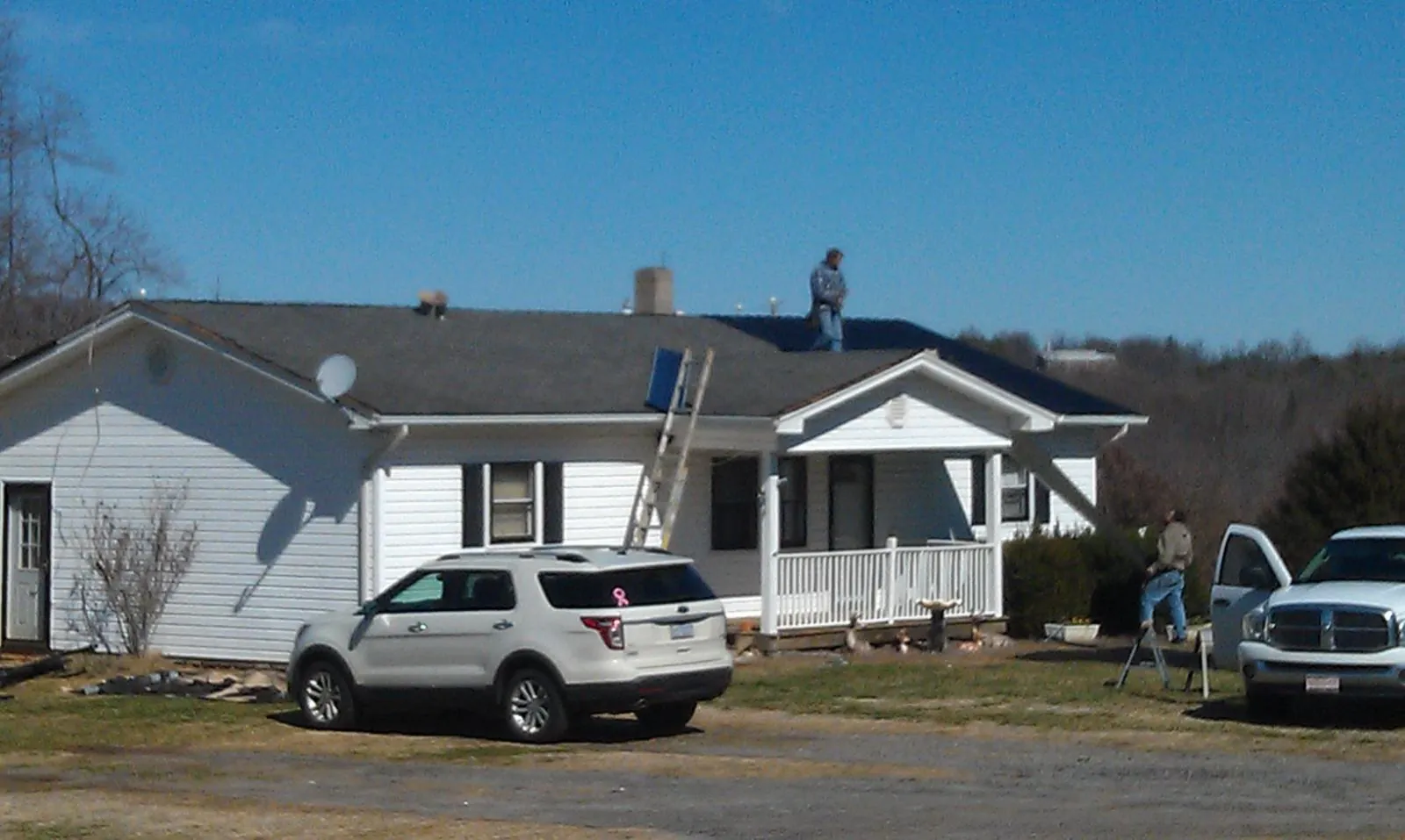 Roofers stripping shingles from a white ranch house roof in Grandview
