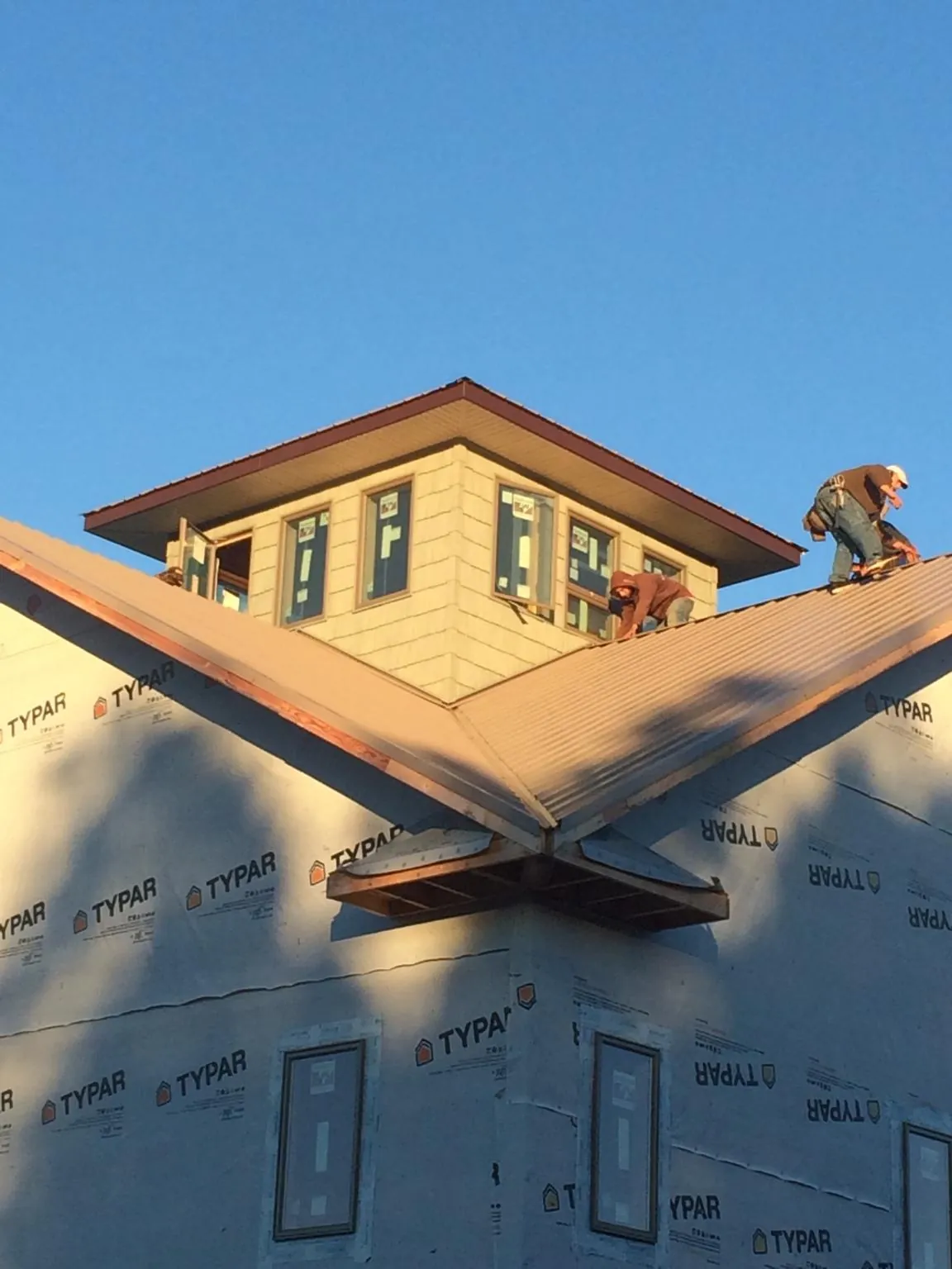 Roofers working around a rooftop cupola on a new metal roof at sunset — Roof Waterproofing in Grandview by Roofing Brothers